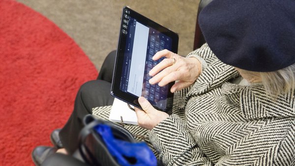 Eine ältere Frau aus der Vogelperspektive, die auf einem Tablet tippt