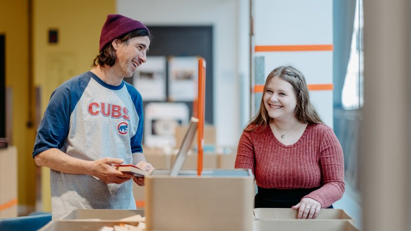 Zwei Personen im Gespräch zwischen Bücherregalen