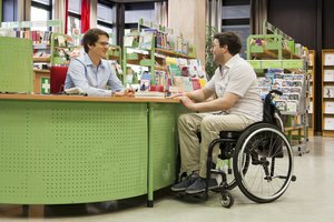 Rollstuhlfahrer an der Informationstheke