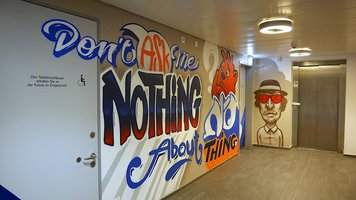 Graffiti im Gang zu Aufzug und Toiletten