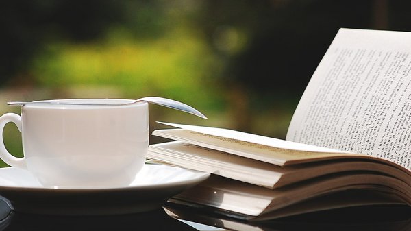 Tasse neben aufgeschlagenem Buch