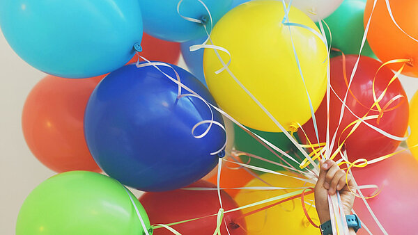 Hand hält Luftballons