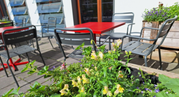 Ein Blumenbeet und Tische und Stühle im Hintergrund.