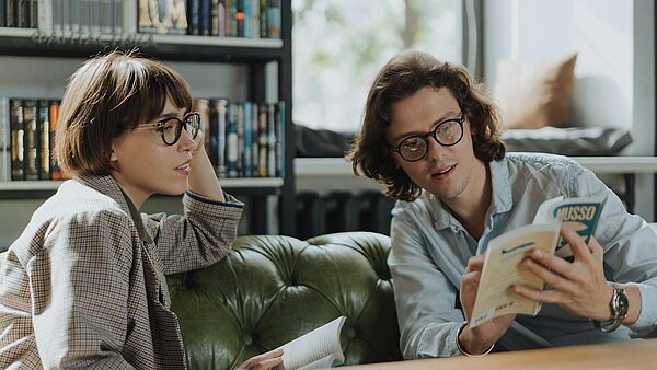 zwei Personen mit Büchern im Gespräch
