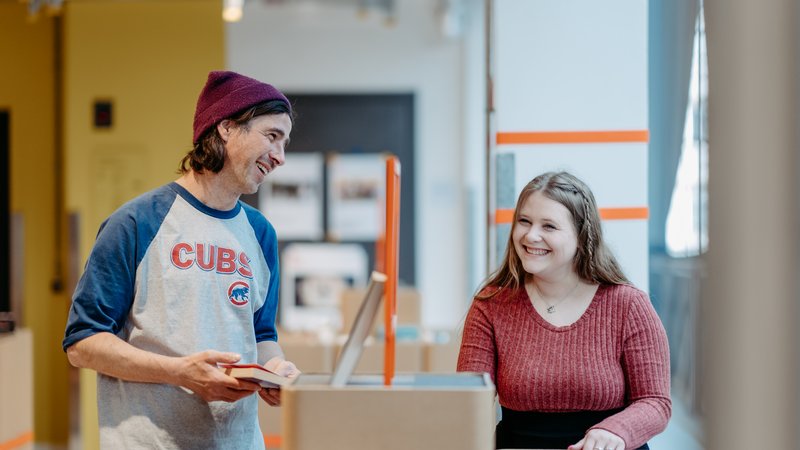 Zwei Personen im Gespräch zwischen Bücherregalen