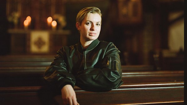 Frau sitzt auf Kirchenbank, im Hitnergrund ist der Altar zu sehen