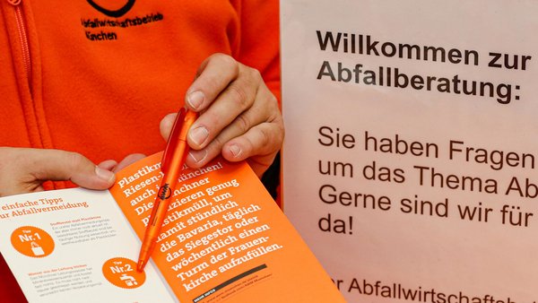Person zeigt mit Kugelschreiber auf Broschüre über die Abfallwirtschaft München (AWM).